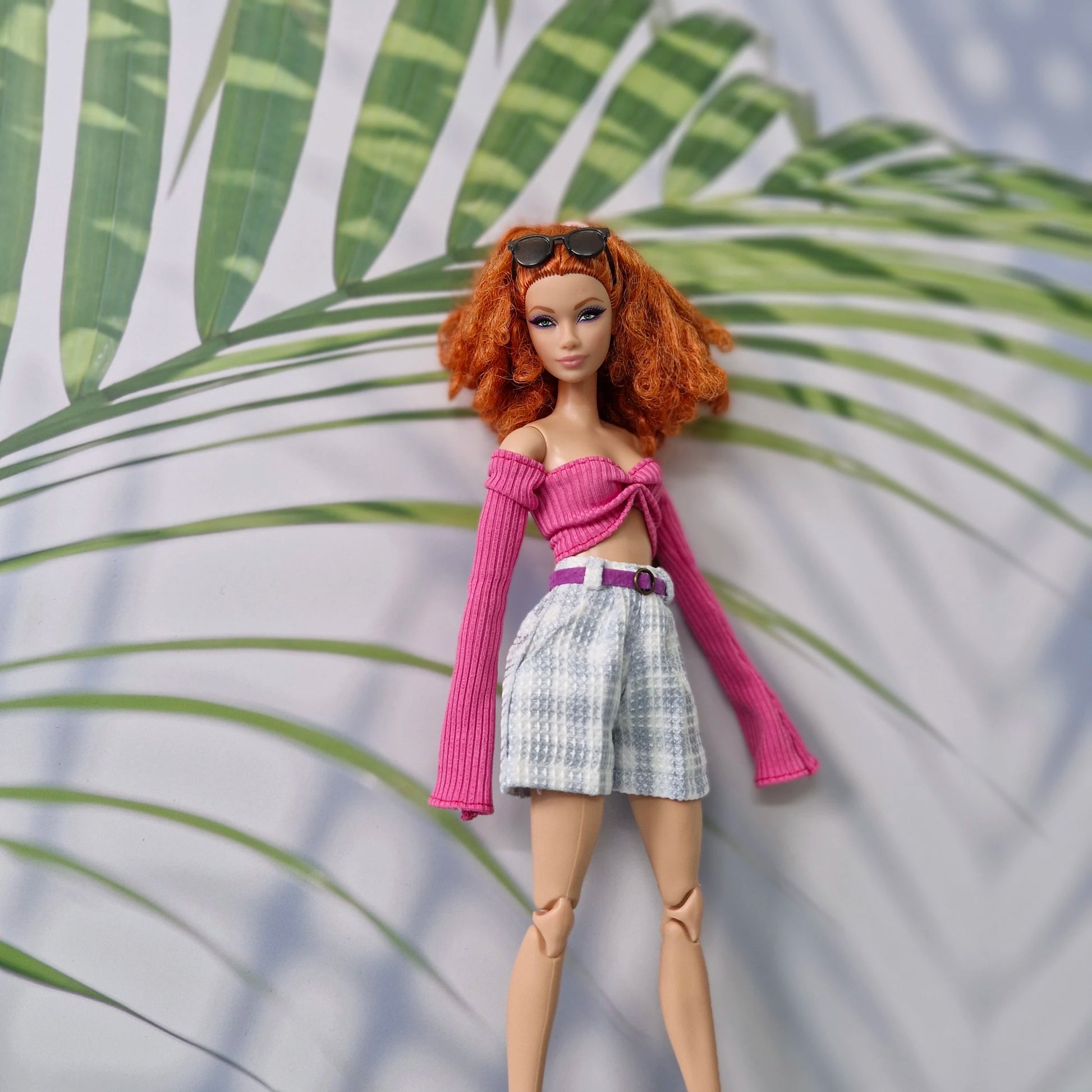 Red-haired Barbie modeling a dark pink long-sleeve top and blue plaid shorts outfit.