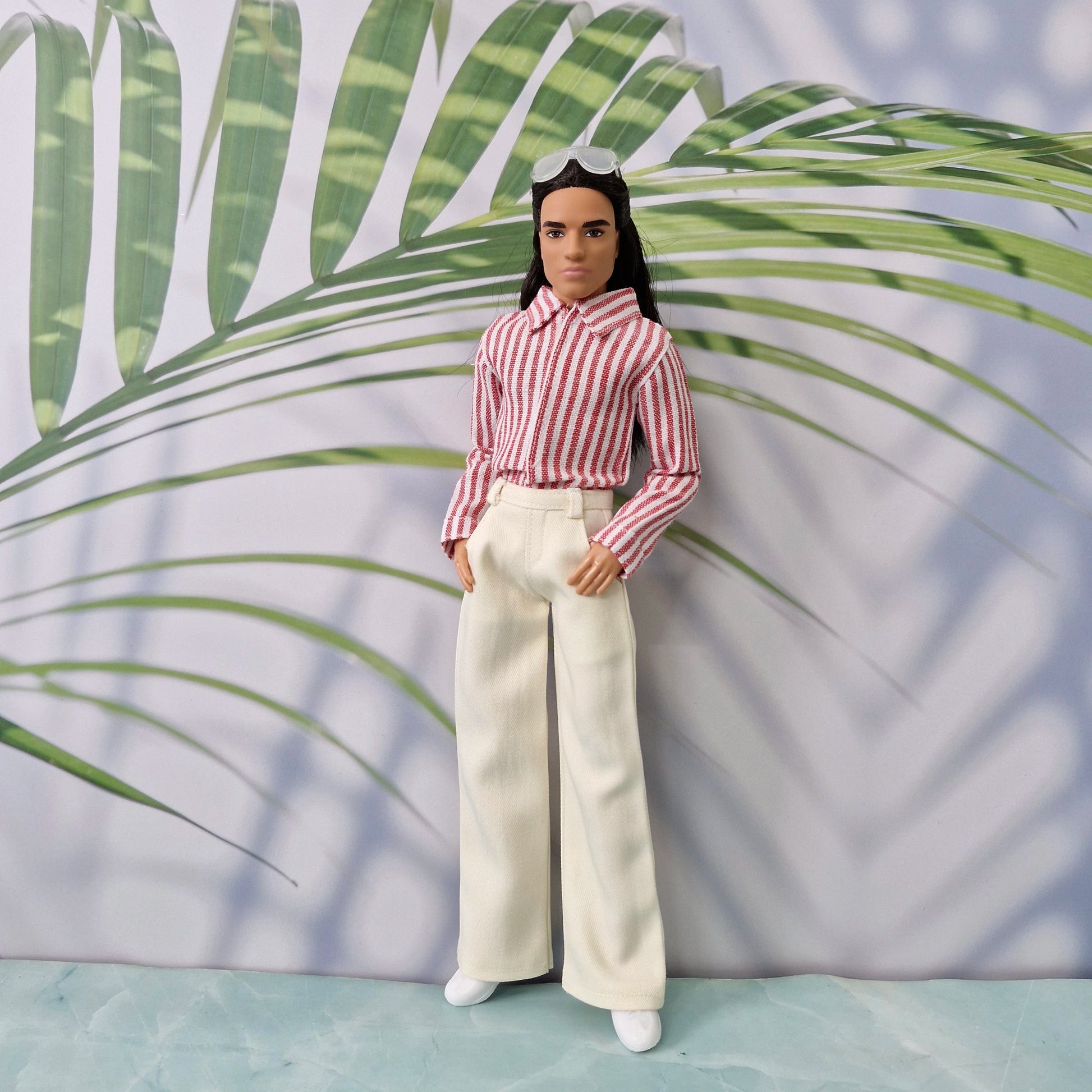 Ken doll wearing a handmade blue and white striped shirt tucked into dark blue trousers.