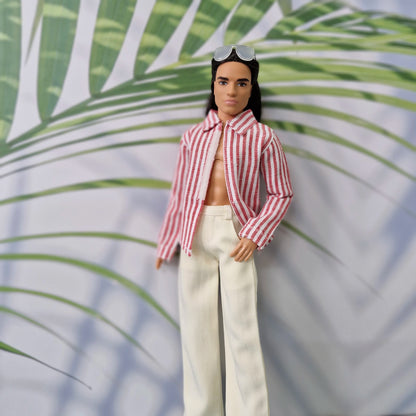 Close-up of a Ken doll in a handmade open red striped collared shirt and white trousers.
