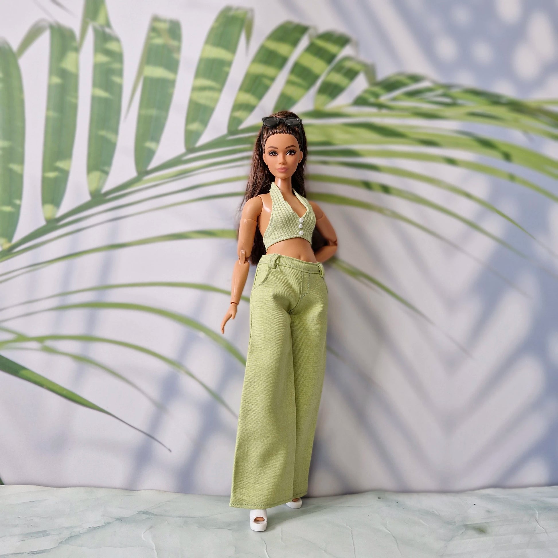 Full body shot of a Curvy Barbie wearing a handmade green summer top and pants outfit with white shoes.