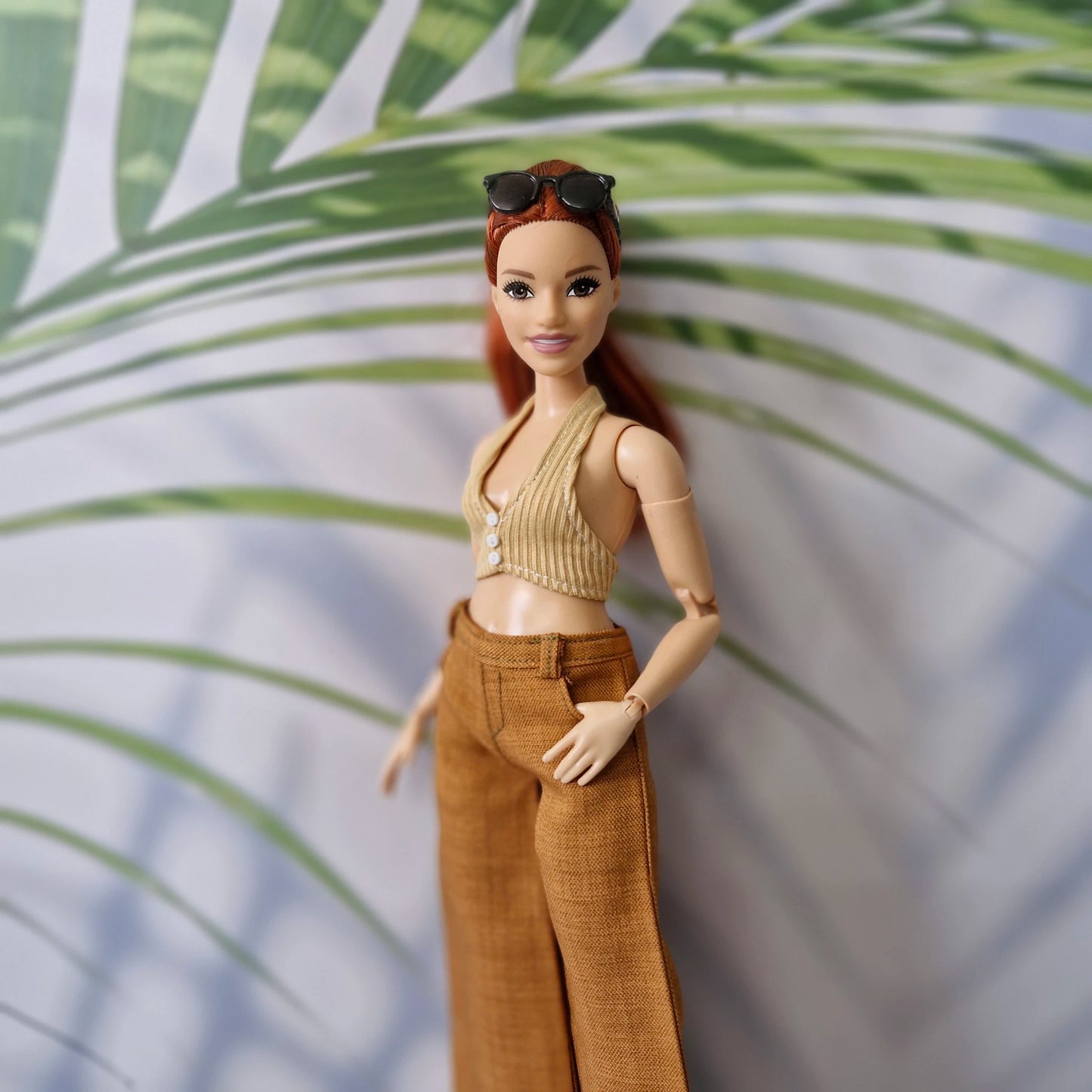 Close up of a red-haired Curvy Barbie doll wearing a handmade beige halter top and brown pants.