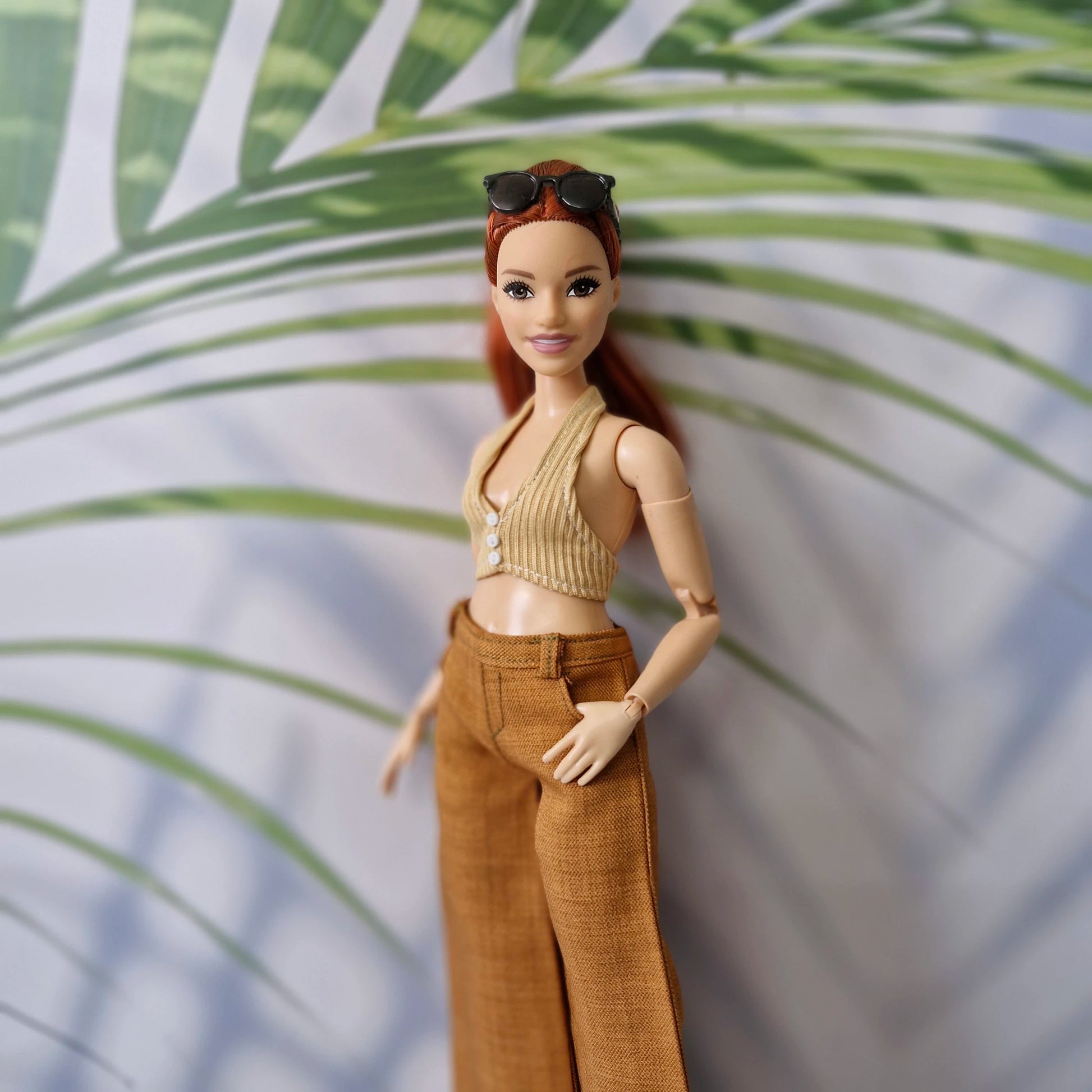 Close up of a red-haired Curvy Barbie doll wearing a handmade beige halter top and brown pants.