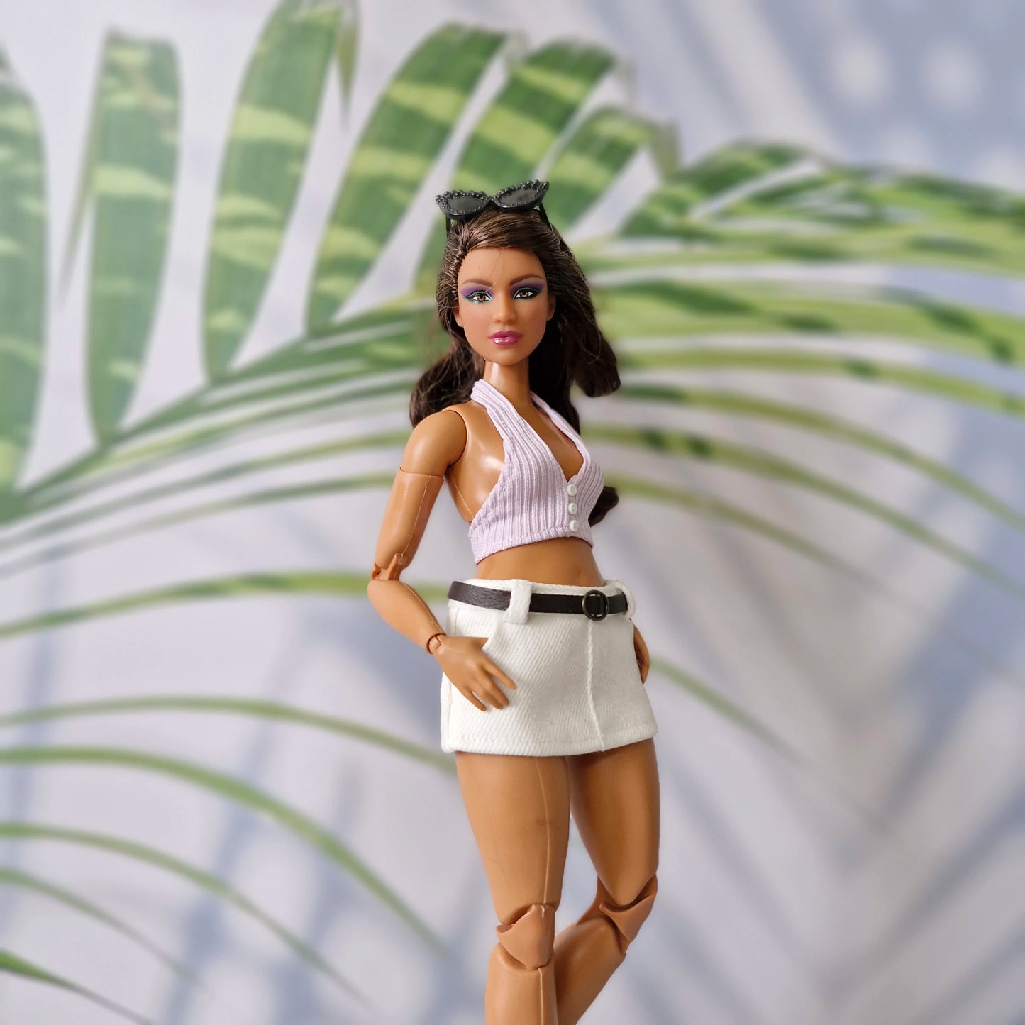1/6 scale Curvy fashion doll wearing a handmade pastel purple summer top and white skirt with a brown belt.