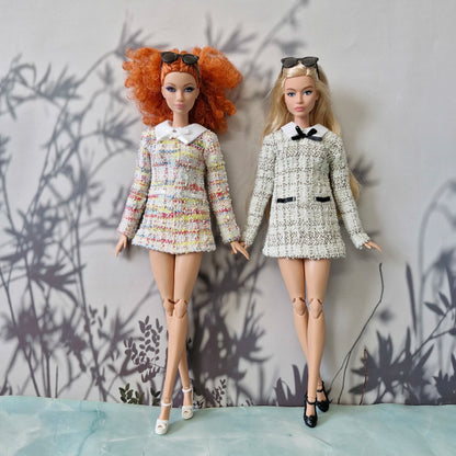 Two standard Barbie dolls holding hands, wearing handmade classic tweed dresses in colorful and black-and-white.