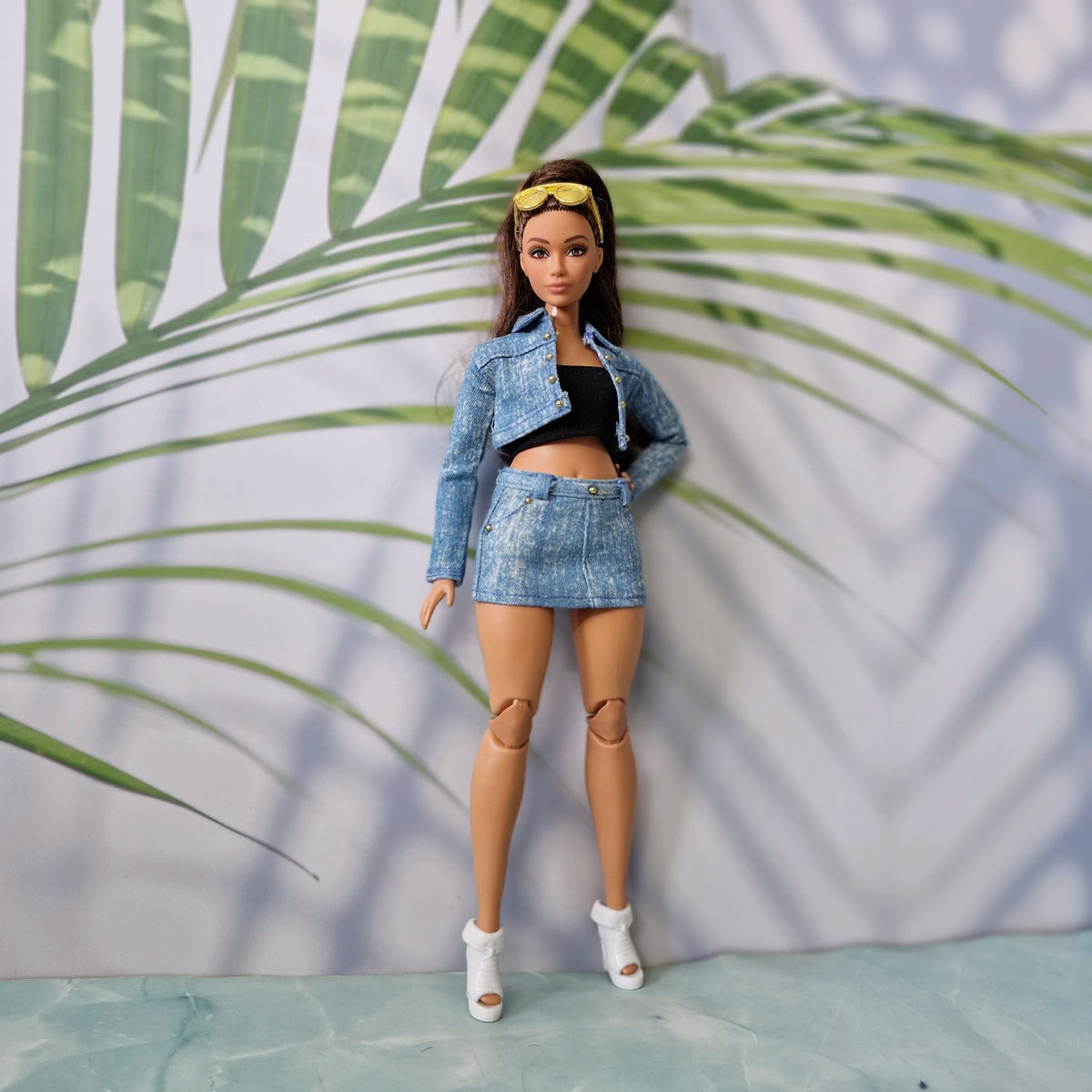 Full body shot of a Curvy Barbie doll wearing a handmade light blue denim jacket, black tube top, and denim mini skirt.