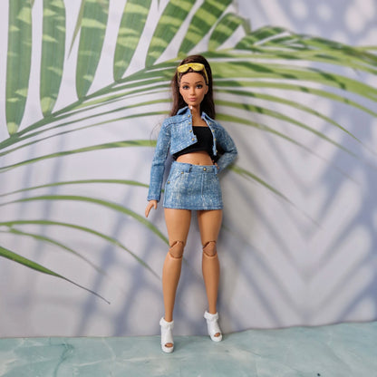 Full body shot of a Curvy Barbie doll wearing a handmade light blue denim jacket, black tube top, and denim mini skirt.