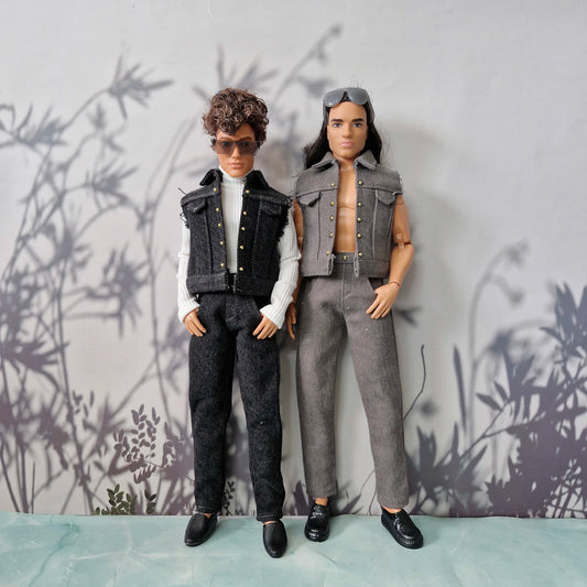 Two Ken dolls standing together; one wearing a white turtleneck and dark denim outfit, the other in a grey denim vest and jeans.