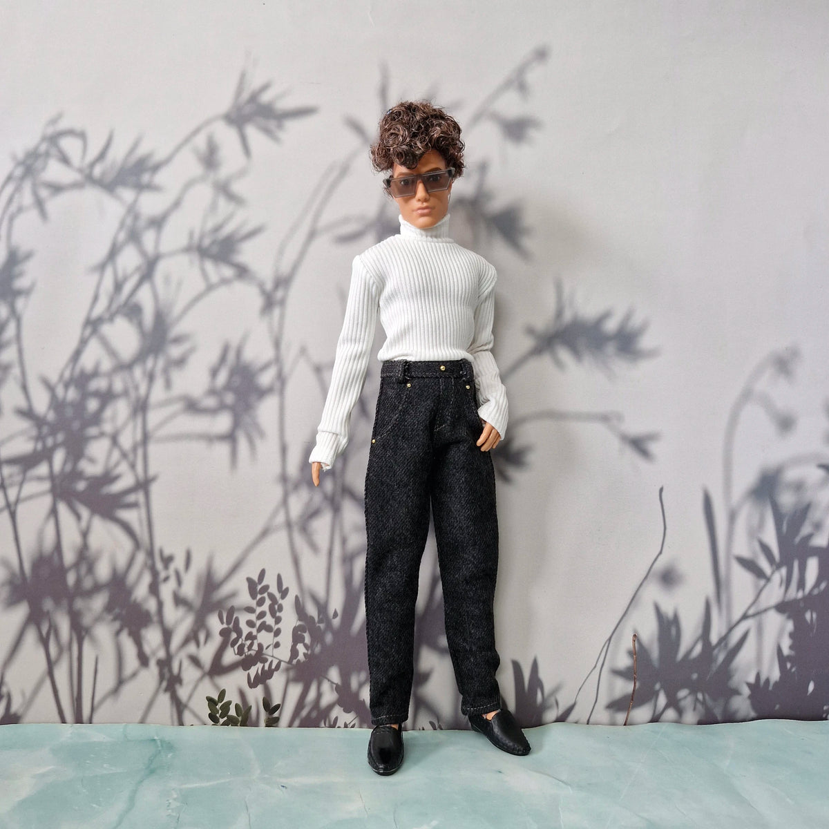 Full body shot of a Ken doll wearing a classic white ribbed turtleneck top and dark wash denim jeans.
