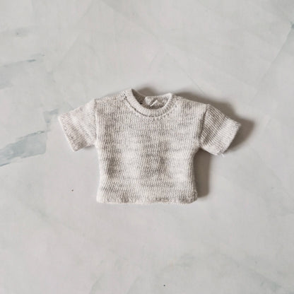 Light grey heather knit short-sleeve crop top for Barbie doll, laid flat on marble background.