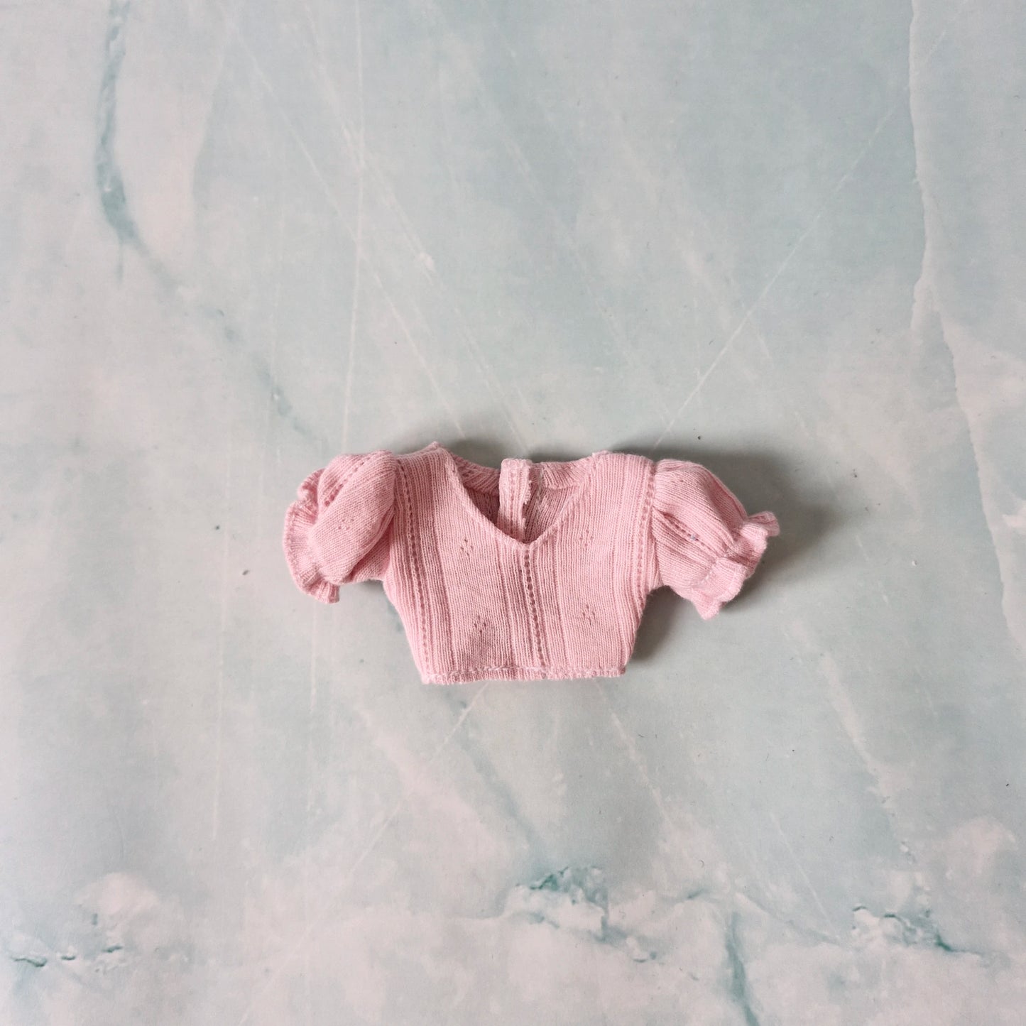Pink knitted baby outfit on a marble surface