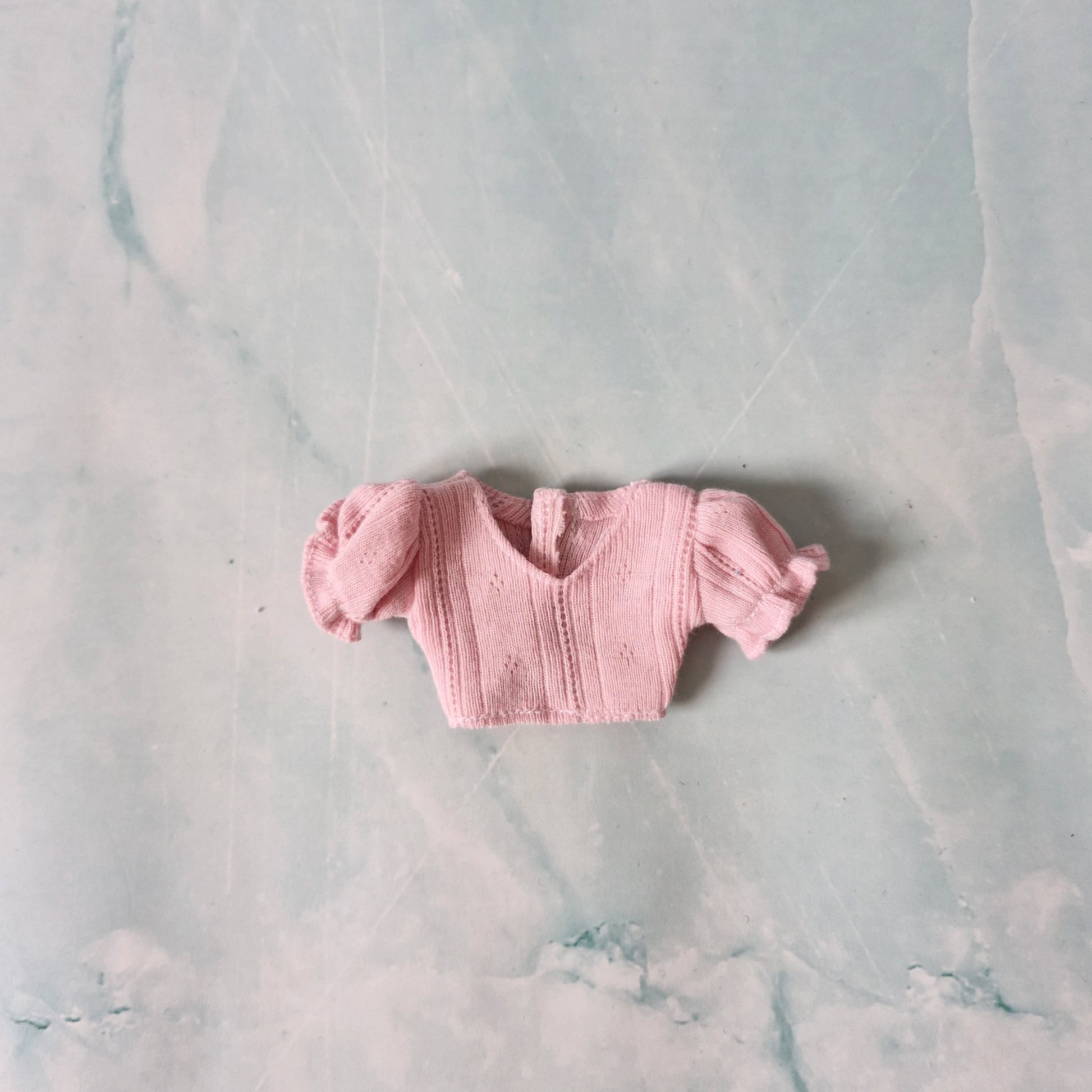 Pink knitted baby outfit on a marble surface