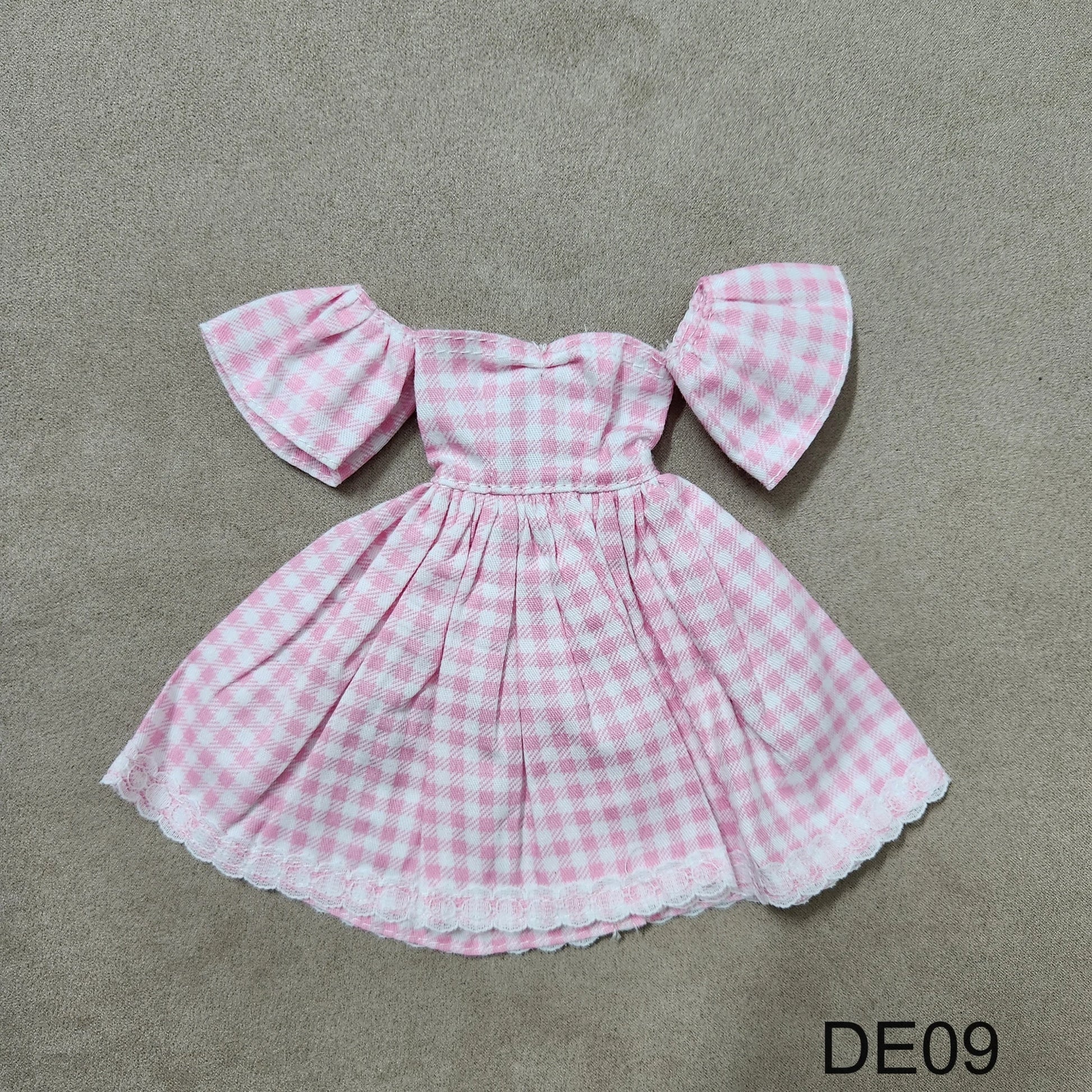 Pink gingham off-shoulder Barbie dress DE09 laid flat on fabric background