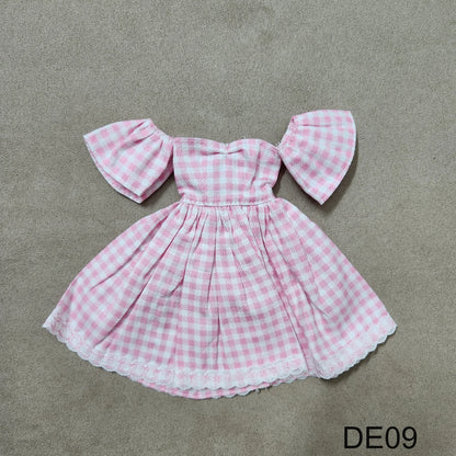 Pink gingham off-shoulder Barbie dress DE09 laid flat on fabric background