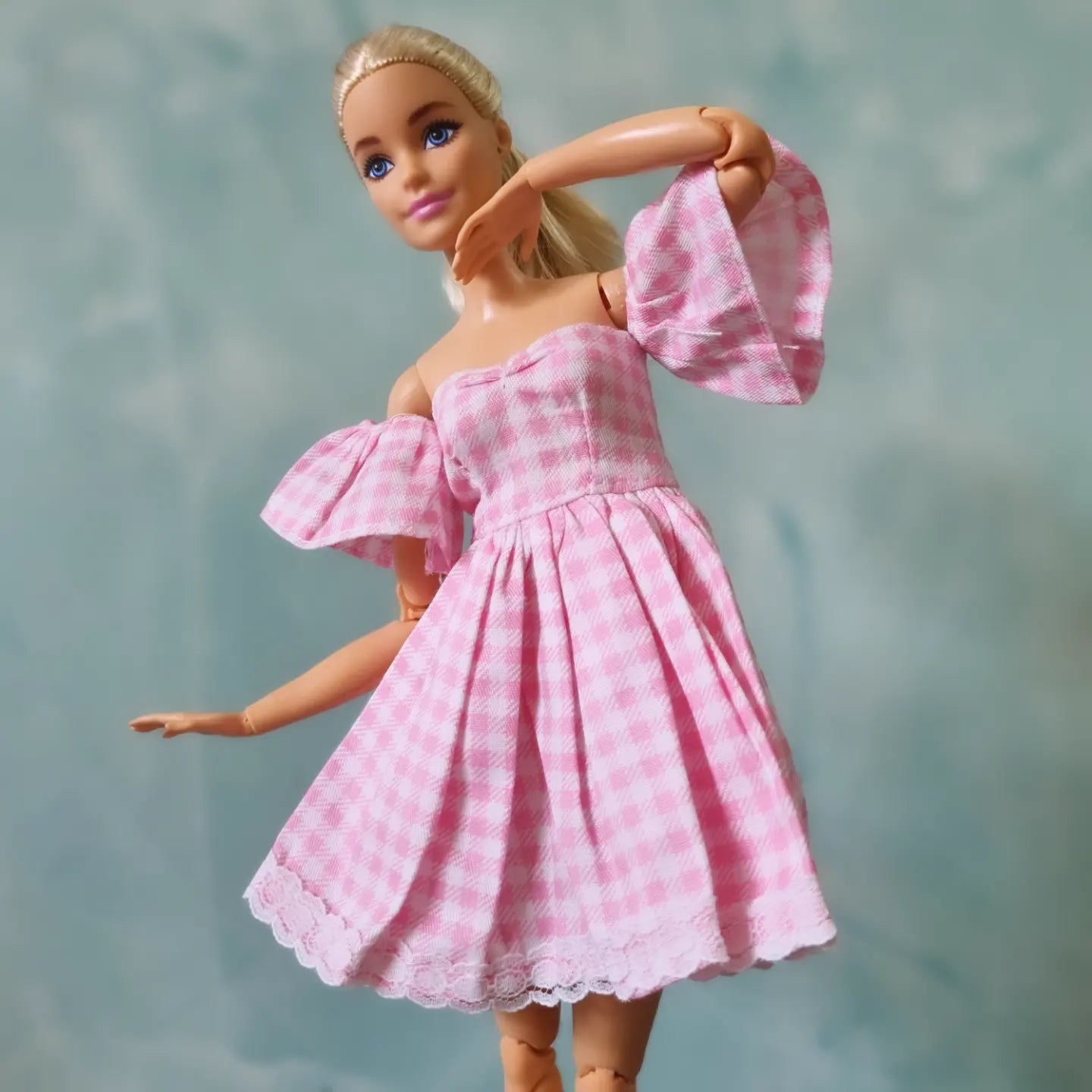 Barbie posing in pink gingham puff sleeve dress with flared skirt
