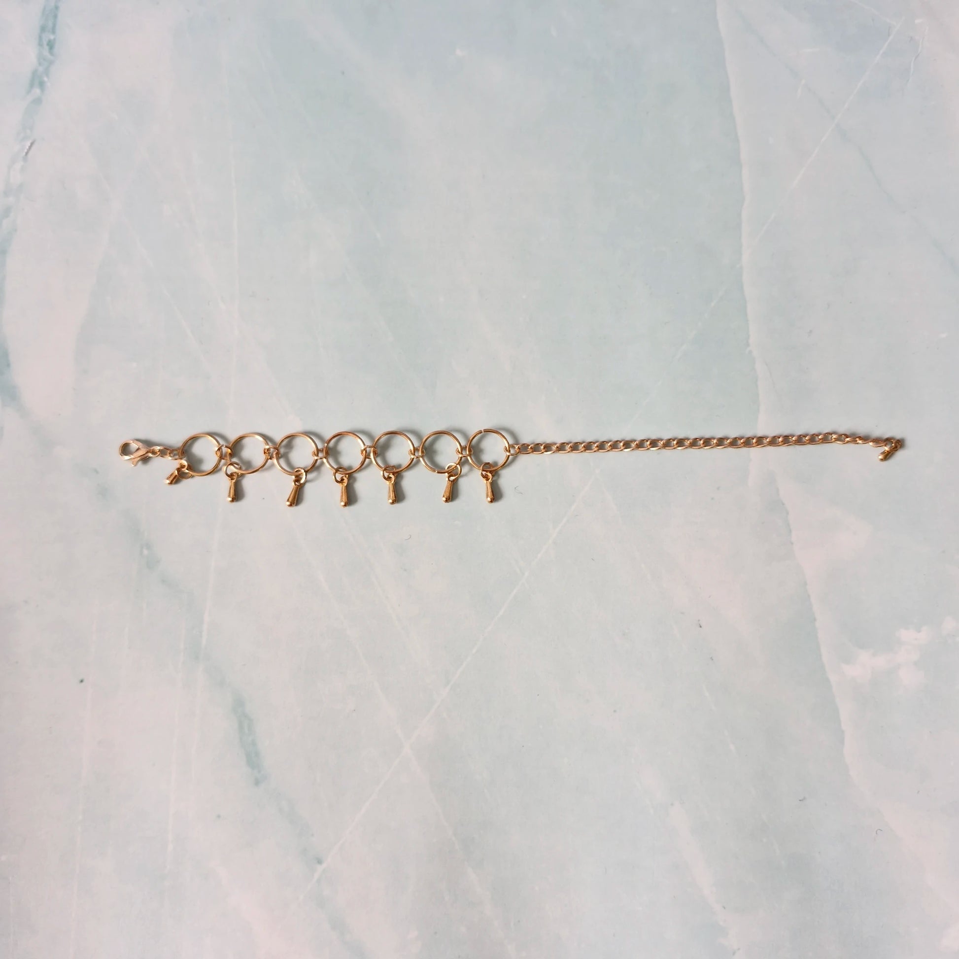 Gold bracelet with small charms on a marble surface