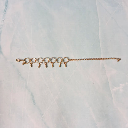 Gold bracelet with small charms on a marble surface